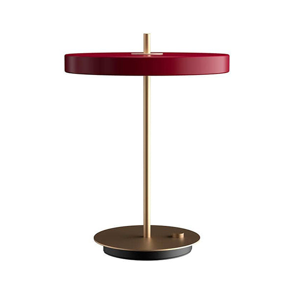 La lampe de table Asteria par Umage dispose d'un panneau LED intégré avec un diffuseur assurant un éclairage doux dans la pièce. La tige en laiton traversant la lampe de table comme un axe vertical renforce une expression serrée et épurée.