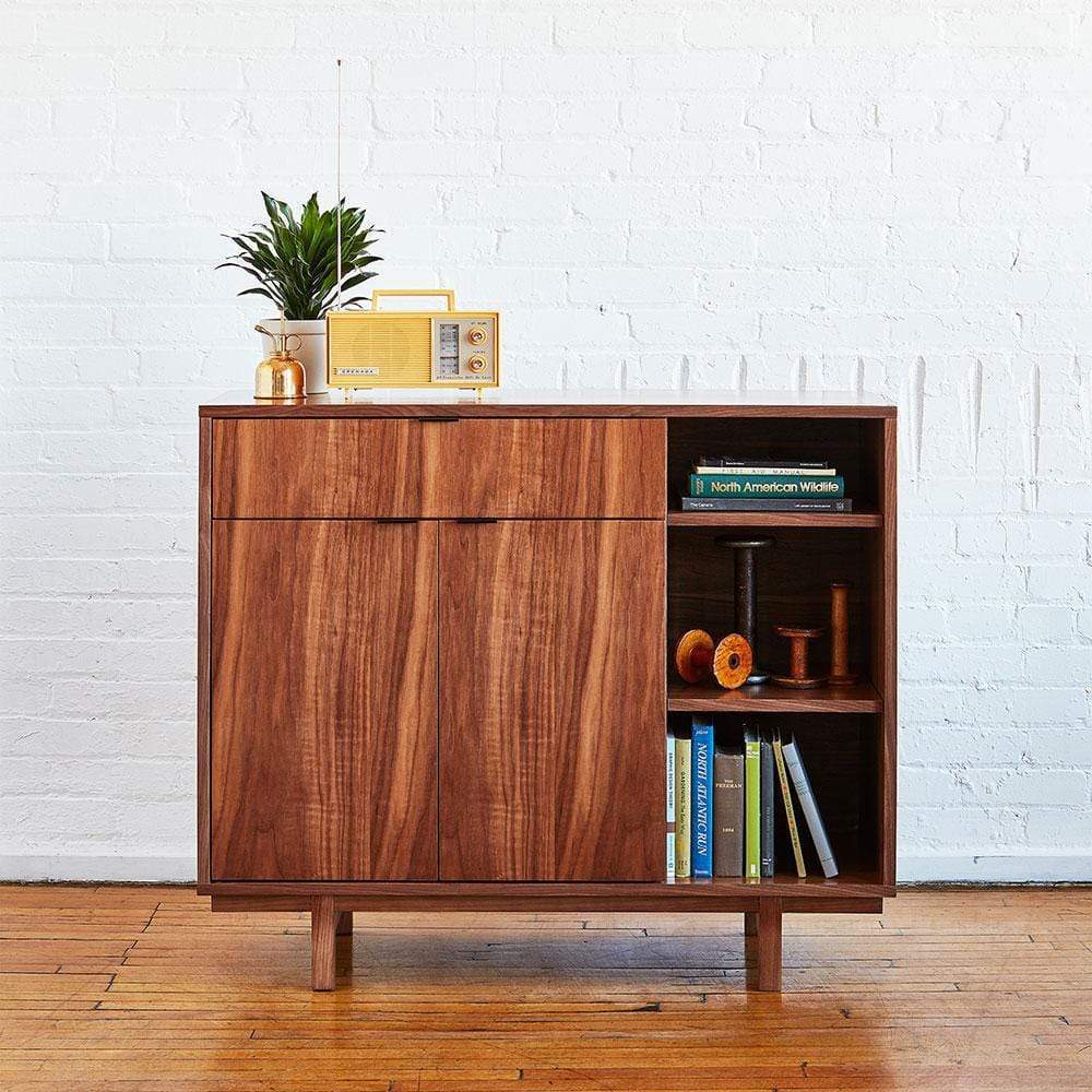 Le cabinet Belmont de Gus* Modern est un concept de rangement inspiré de l'architecture qui met en valeur le noyer. Les portes dissimulent une tablette ajustable et, avec le tiroir supérieur, sont dotées de poignées contrastées au fini noir.