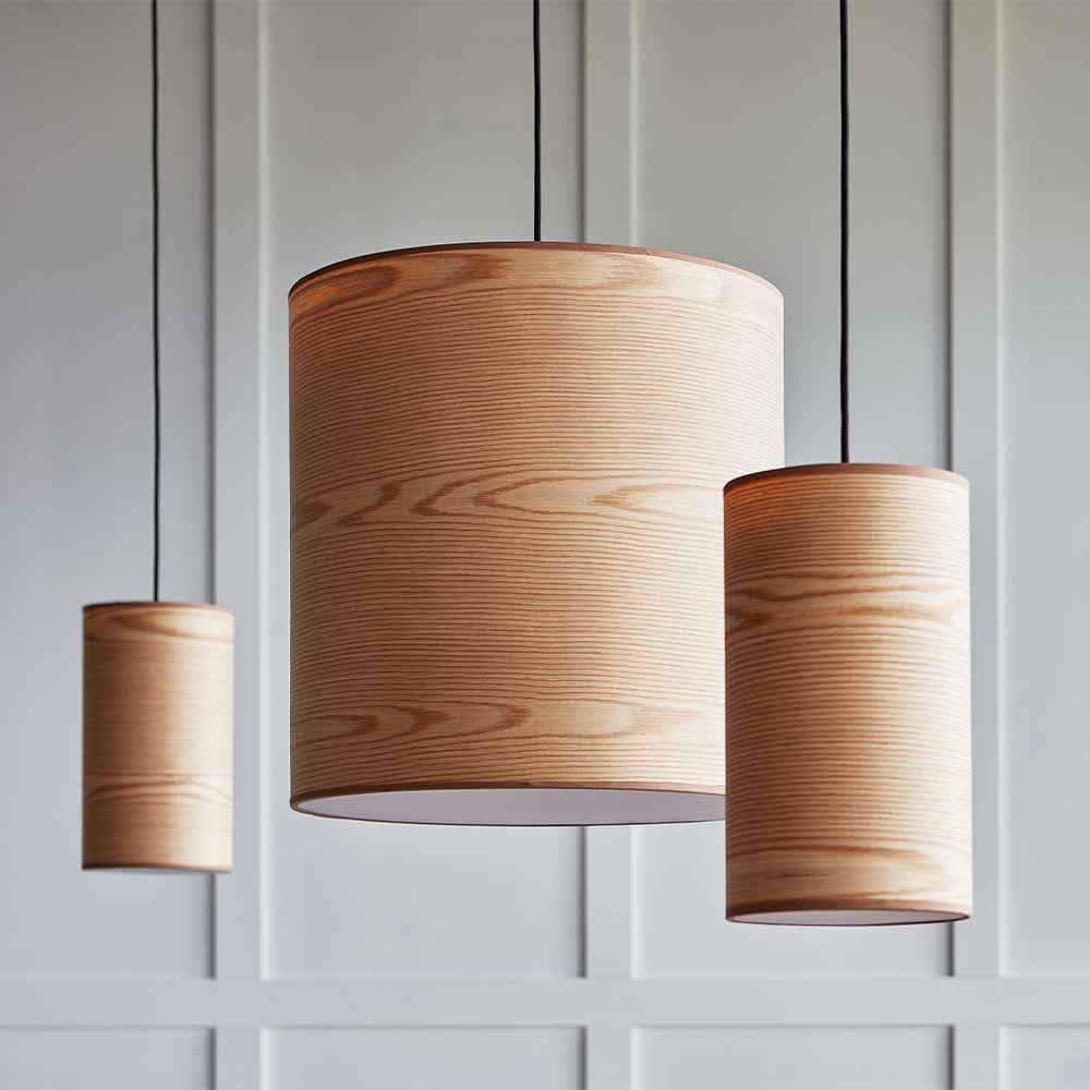 Chaque lampe suspendue Milton de Gus* Modern est enveloppée d'un abat-jour en placage de bois naturel, avec un cordon électrique en tissu noir qui laisse l'attrait rustique de l'éclairage occuper le devant de la scène.